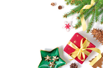 The gift wrapped in red wrapping paper is tied with a yellow ribbon with a bow. Natural spruce branch, cones and decorations are nearby. Christmas composition. Flat lay. Top view. Copy space.