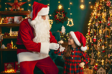 Fototapeta na wymiar Santa Claus with a little cute girl play in the room. Christmas time.