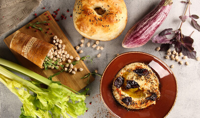 Oriental cuisine. Hummus. Appetizer of chickpeas, tahini, olive oil, lemon and celery root in a brown bowl on a gray table. Tandoor braed, eggplant, basil. Rustic. Copy space. Flatlay, top view