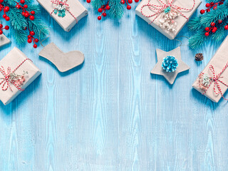 Christmas composition. Gifts in craft paper are tied with a striped ribbon. Coniferous branches, cones and decorations are nearby. Blue wooden background. Flat lay, top view, copy space.