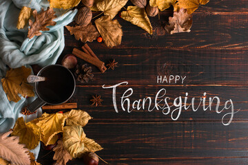 Thanksgiving greetings. Tea in a mug, dry leaves and spices on a dark background, top view. Kaligraphic capital inscription.