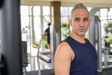 Fototapeta na wymiar Portrait of mature handsome Persian man at the gym ready to exercise