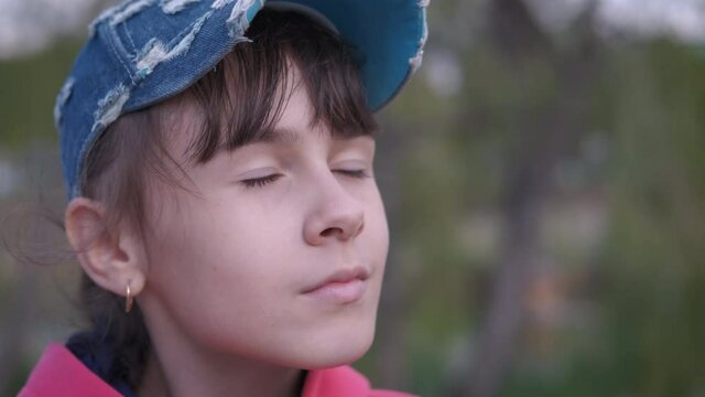 Teen without mask. A child takes off her black protective mask and smile breathing with fresh air in the park.