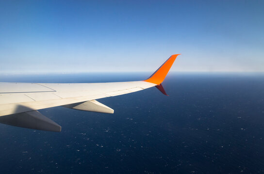 Airplane wing flying over the ocean