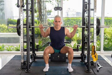 Fototapeta na wymiar Mature handsome Persian man lifting weight at the gym