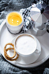 Cup of coffee on tray in cozy winter bad with wool blanket