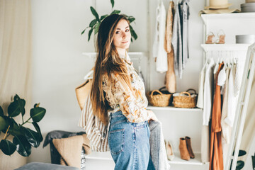 Long haired brunette woman chooses clothes in the wardrobe at home.