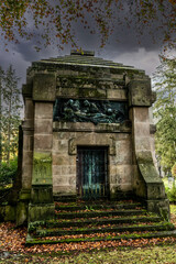 Fototapeta na wymiar schönes altes Mausoleum mit einer Gittertüre und einer großen Bronzeplatte 