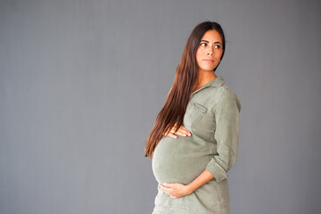 schwangere Frau vor grauer Wand