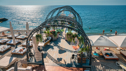 fragment of a pebble beach with a gazebo for recreation and peoples having a rest on the beach
