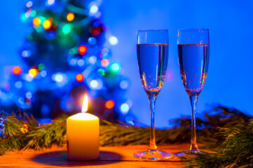 two glasses of champagne on the background of a Christmas tree and a candle. festive atmosphere of comfort and romance in the new year for a couple