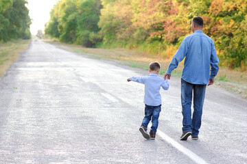 A Happy parent with a child in the park hands on nature travel go along the road