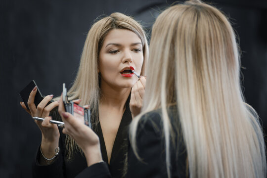 Woman applying lipstick looking to the mirror