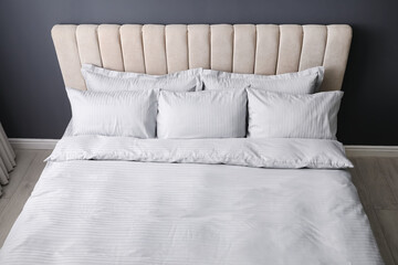 Comfortable bed with soft blanket and pillows indoors