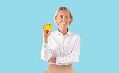 Portrait of businesswoman showing gold credit card over blue studio background, panorama