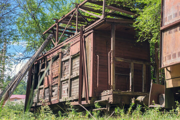 Old abandoned wooden cargo train carriage overgrown with plants