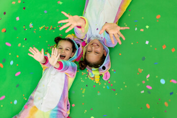 two girls in bright costumes on a green background with confetti. The concept of a holiday, Birthday and sales