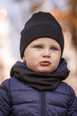 Little boy in a black hat looks at the camera. Portrait of a child close up