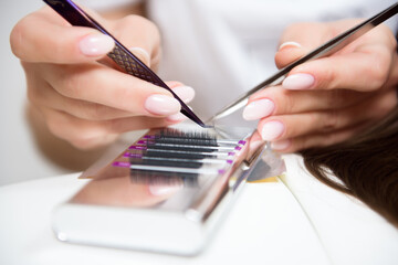 Beautician working on upgrading silk eyelashes in a beauty studio.