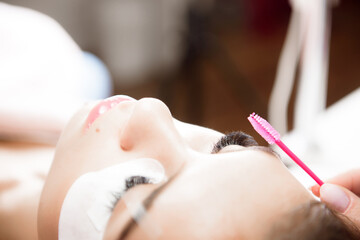 Obraz na płótnie Canvas Beautiful young woman during eyelash extension, Close up.