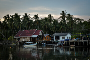 Fototapeta na wymiar wooden houses at pier with palmtree background in evening time in thailand