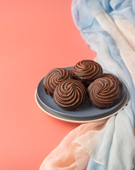 Traditional Russian vanilla marshmallows in chocolate glaze in blue and white plates on pink background. Colorful table and delicate gradient textiles. Vertical