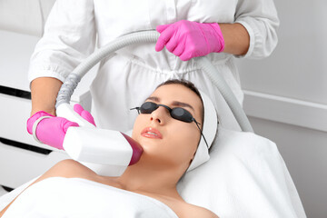 Naklejka premium Elos epilation hair removal procedure on the face of a woman. Beautician doing laser rejuvenation in a beauty salon. Facial skin care. Hardware ipl cosmetology