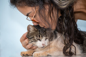 A brunette woman kissing and petting her cat. Animal world. Pet lover. Animals defender. Cat lover. American Wirehair