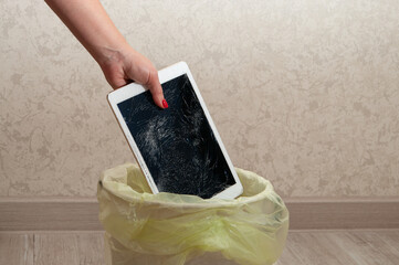 Woman throws it in the litter bin modern tablet with highly broken screen.