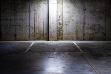 Empty parking lot with overhead dim light, underground parking garage.