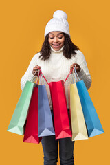 Excited black lady holding shopping bags looking inside