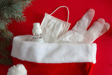 Santa Claus hat with gifts in the form of disposable gloves, a medical mask and hand sanitizer, the idea of the new year 2021 holiday in quarantine by Covid