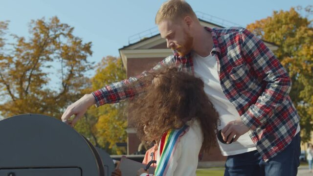 Caucasian Man with african daughters throwing garbage in metal container outdoors