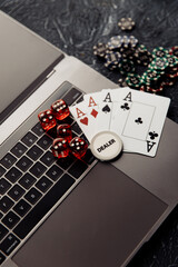 Online casino. Gambling chips, cards with aces and red dices on laptop keyboard. Vertical image.