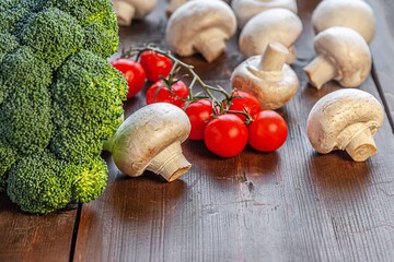 broccoli, mushrooms and cherry tomatoes on a wooden surface