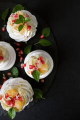 dessert called Anna Pavlova. Meringue with cream garnished with pomegranate, tangerine slices and Basil leaves