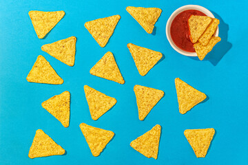 flat lay nachos chips and chili sauce on a blue background close up