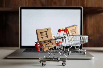 Boxes in trollies on a laptop keyboard. Business, ecommerce and shopping concept.