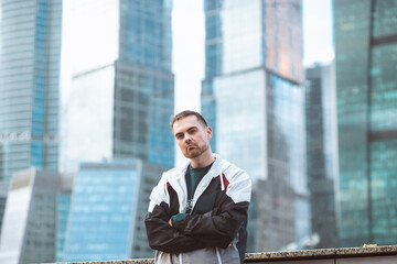 Fototapeta premium Handsome casual man in windbreaker standing on a skyscraper view. Sports style and business.