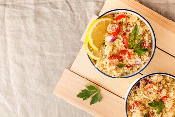 Flatlay Tabouleh is an Arabic vegetarian salad made with couscous, tomatoes, parsley, onion and lemon juice. Copy space.