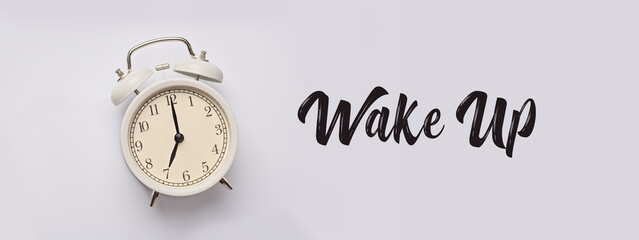 Alarm clock on the background with words Wake Up. 7 am. Banner