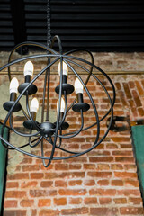 round chandelier, gold, brass, different shapes of a circles, inside lamp there are candles. Fashion design chandeliers.Old fashioned lantern.lamps hanging at restaurant over brick background