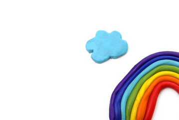 Plasticine rainbow near blue clouds on white background