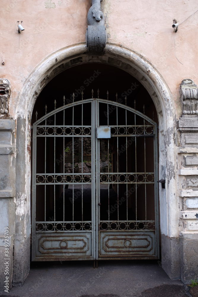 Poster an old gateway with an iron gate. vertical frame