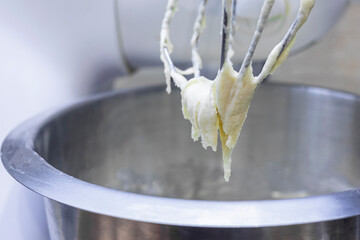 Butter with sugar on the Corolla of the kitchen machine, mixer. Selective focus.