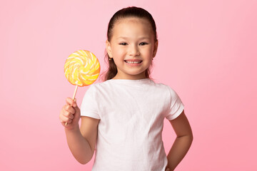 Adorable asian girl smiling and holding colorful lollipop