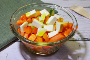 Salad with vegetable cucumber, tomatoes and cheese in transparent bowl