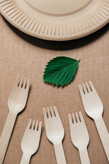 Wooden forks and plates on kraft paper background. Eco friendly disposable tableware. Also used in fast food, restaurants, takeaways, picnics. Top view. Copy, empty space for text