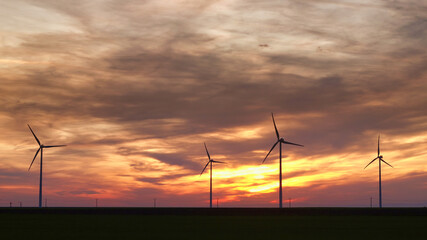 Obraz premium Wind turbine silhouette on beautiful sunset landscape 