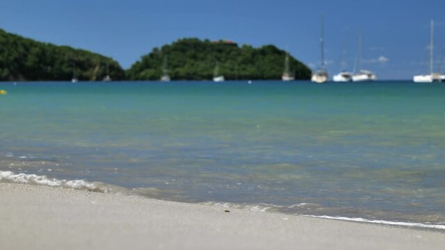 Slow motion of waves breaking on a white sand beach islet ramier in background Martinique anse a l'ane
